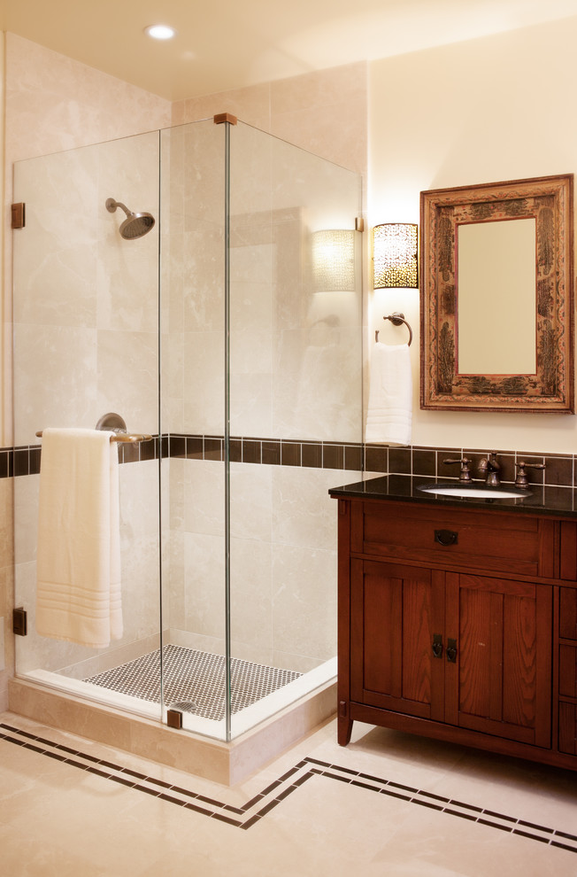 This is an example of a traditional bathroom in San Francisco with a submerged sink, dark wood cabinets, a corner shower, beige tiles and shaker cabinets.