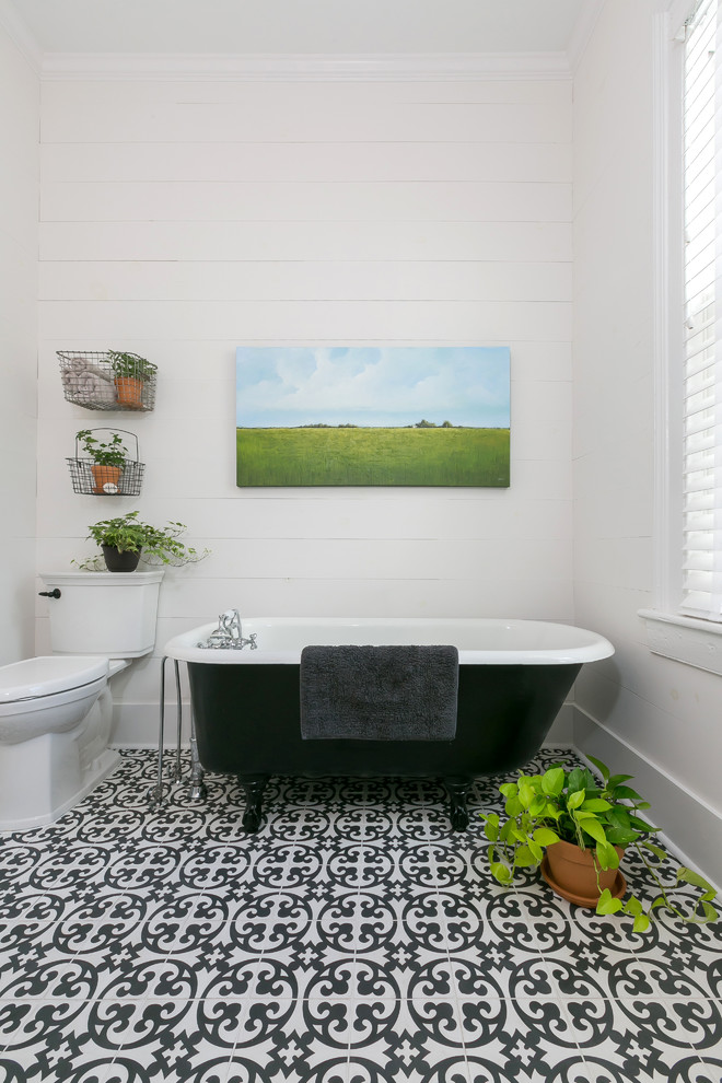 Cette photo montre une salle de bain principale nature de taille moyenne avec un placard à porte shaker, des portes de placard blanches, une baignoire sur pieds, WC à poser, un carrelage noir et blanc, un mur blanc et un lavabo encastré.