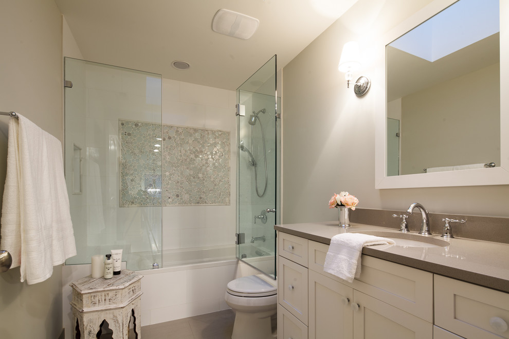 シカゴにあるトランジショナルスタイルのおしゃれな浴室 (アンダーカウンター洗面器、シェーカースタイル扉のキャビネット、ベージュのキャビネット、アルコーブ型浴槽、シャワー付き浴槽	、白いタイル) の写真