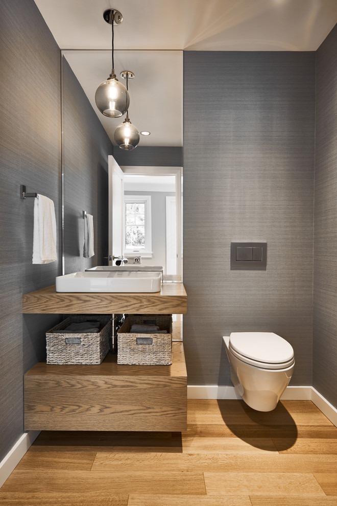 Imagen de cuarto de baño tradicional pequeño con sanitario de pared, paredes grises, suelo de madera clara, aseo y ducha, lavabo sobreencimera, encimera de acrílico, suelo beige y encimeras beige