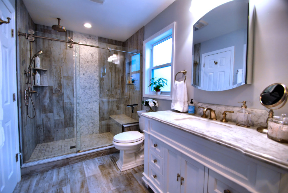 На фото: главная ванная комната среднего размера в стиле кантри с фасадами островного типа, белыми фасадами, накладной ванной, душем в нише, раздельным унитазом, коричневой плиткой, галечной плиткой, серыми стенами, полом из керамогранита, врезной раковиной, мраморной столешницей, коричневым полом, душем с раздвижными дверями и разноцветной столешницей