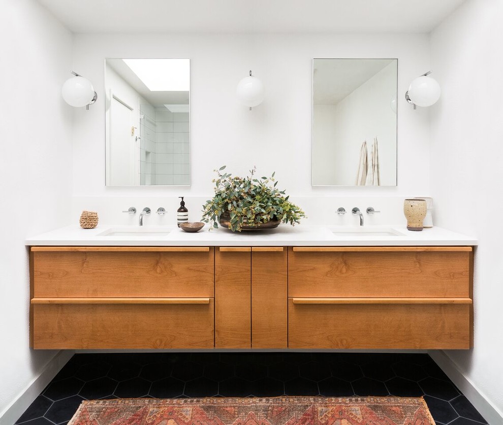 Large midcentury ensuite bathroom in Seattle with flat-panel cabinets, medium wood cabinets, white tiles, porcelain tiles, white walls, porcelain flooring, a submerged sink, solid surface worktops and black floors.