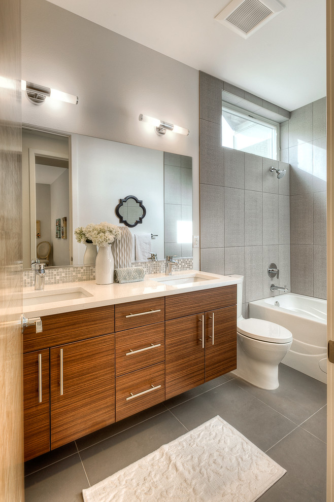 Example of a mid-sized kids' gray tile and porcelain tile porcelain tile bathroom design in Seattle with an undermount sink, flat-panel cabinets, medium tone wood cabinets, quartzite countertops, a two-piece toilet and gray walls