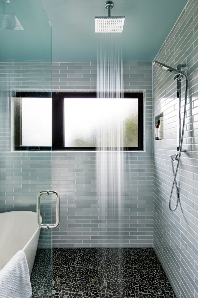 Пример оригинального дизайна: ванная комната в современном стиле с отдельно стоящей ванной, душевой комнатой, синей плиткой, керамической плиткой, полом из галечной плитки, черным полом и душем с распашными дверями
