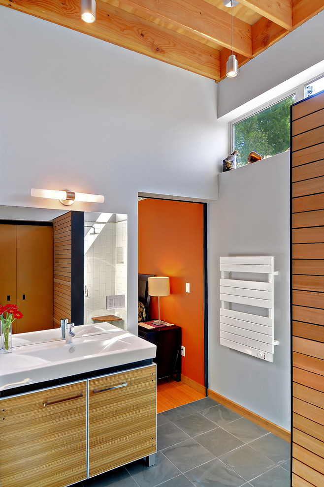 Esempio di una stanza da bagno minimalista con ante lisce, ante in legno chiaro e piastrelle grigie