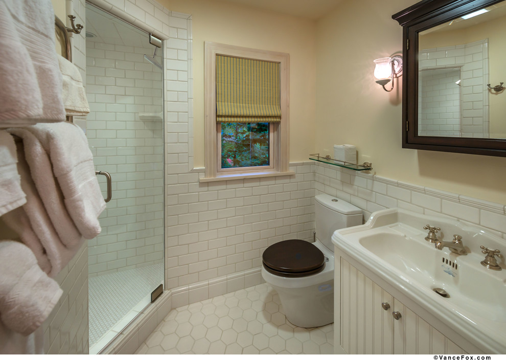 Cette photo montre une salle d'eau nature de taille moyenne avec des portes de placard blanches, une douche ouverte, un carrelage blanc, un mur jaune et un lavabo posé.