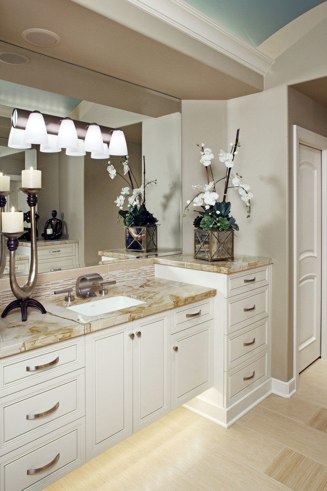 Klassisk inredning av ett stort beige beige en-suite badrum, med luckor med upphöjd panel, vita skåp, beige kakel, stickkakel, beige väggar, laminatgolv, ett undermonterad handfat, bänkskiva i onyx och beiget golv
