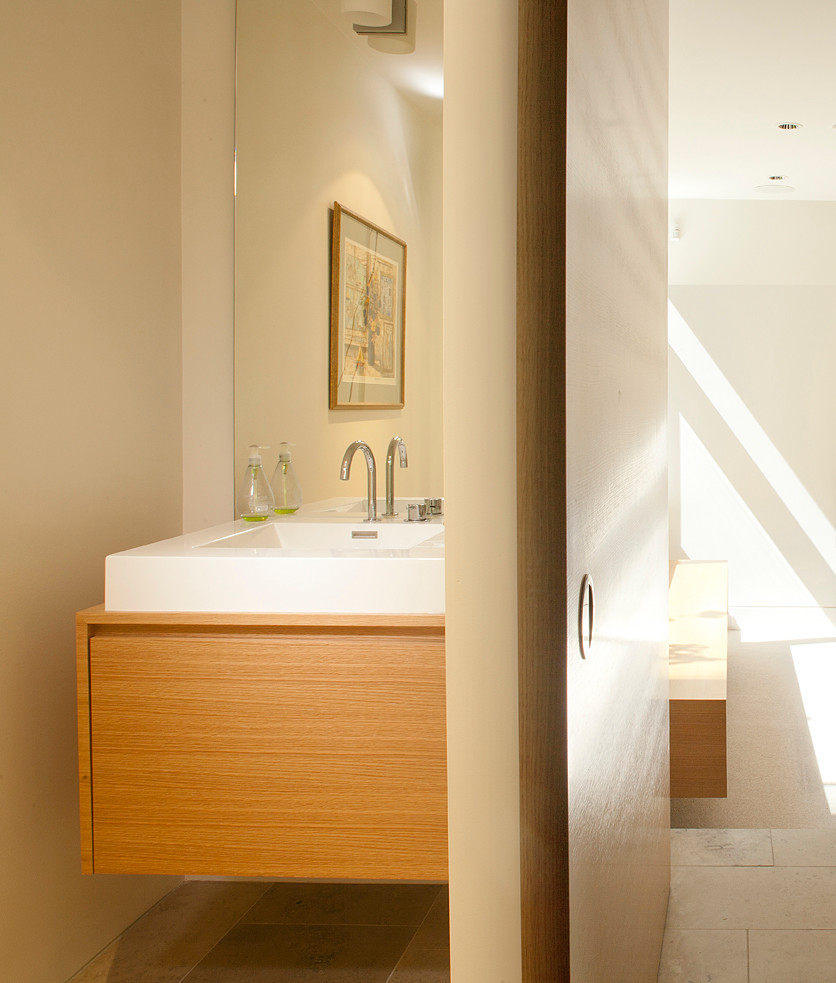 Ispirazione per una stanza da bagno contemporanea con lavabo rettangolare, ante lisce, ante in legno chiaro, pareti beige e pavimento in pietra calcarea