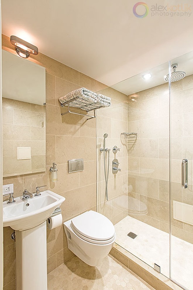 Cette photo montre une salle de bain moderne avec WC suspendus, un lavabo de ferme, un mur beige, un sol en calcaire, un carrelage beige et un carrelage de pierre.