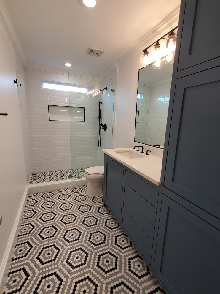 Example of a mid-sized classic kids' white tile and ceramic tile ceramic tile, multicolored floor and single-sink bathroom design in Houston with shaker cabinets, blue cabinets, a one-piece toilet, white walls, a drop-in sink, quartzite countertops, white countertops and a built-in vanity