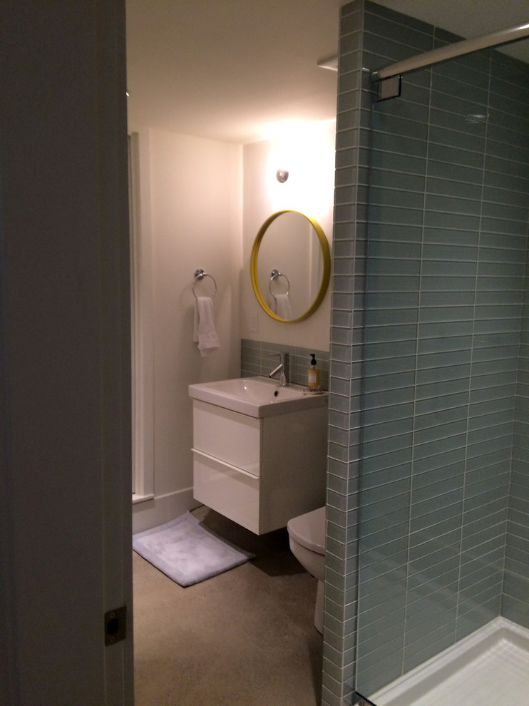 Example of a mid-sized 1950s blue tile concrete floor alcove shower design in Vancouver with an integrated sink, flat-panel cabinets, white cabinets, a two-piece toilet and white walls