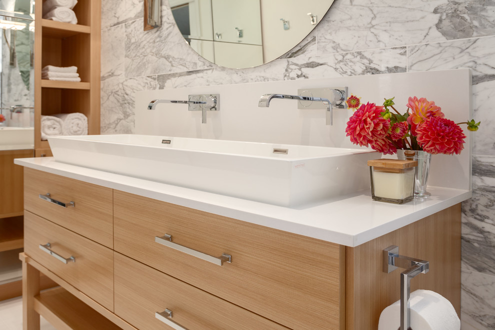Design ideas for a large traditional ensuite bathroom in Vancouver with flat-panel cabinets, light wood cabinets, an alcove shower, a one-piece toilet, multi-coloured tiles, stone tiles, multi-coloured walls, porcelain flooring, a trough sink and engineered stone worktops.