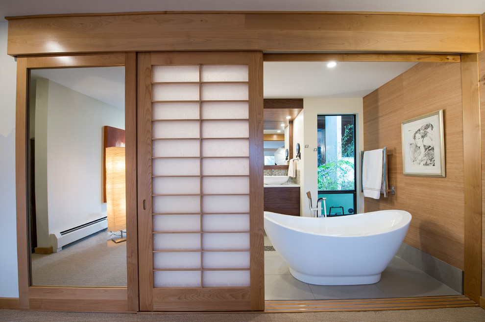 This is an example of a medium sized modern ensuite bathroom in Vancouver with flat-panel cabinets, dark wood cabinets, a freestanding bath, a double shower, a wall mounted toilet, multi-coloured tiles, mosaic tiles, white walls, porcelain flooring, a vessel sink, engineered stone worktops, grey floors and a hinged door.