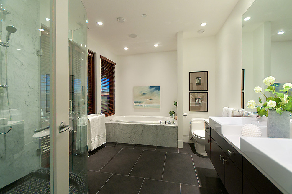 This is an example of a contemporary bathroom in Vancouver with a vessel sink, flat-panel cabinets, dark wood cabinets, a built-in bath, a corner shower, a one-piece toilet and brown tiles.