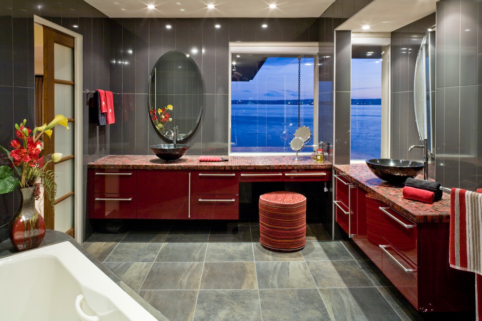 Cette image montre une salle de bain design avec une vasque, des portes de placard rouges et un plan de toilette en carrelage.