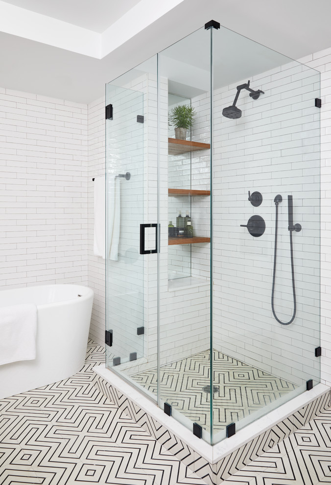 Modern inredning av ett badrum, med ett fristående badkar, en hörndusch, vit kakel, vita väggar, flerfärgat golv och dusch med gångjärnsdörr