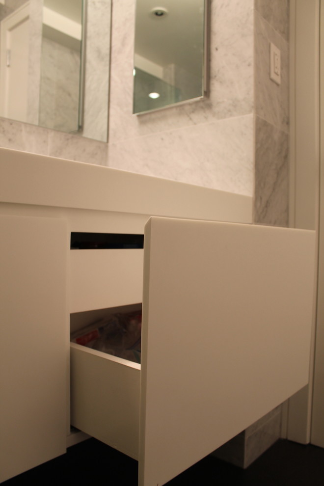 Kleines Modernes Badezimmer mit weißen Schränken, Steinfliesen und Mineralwerkstoff-Waschtisch in New York