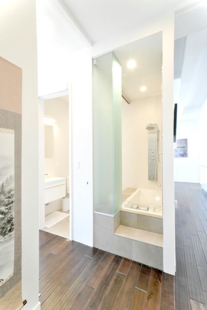 Exempel på ett modernt badrum, med vita skåp, ett platsbyggt badkar, vita väggar och mörkt trägolv