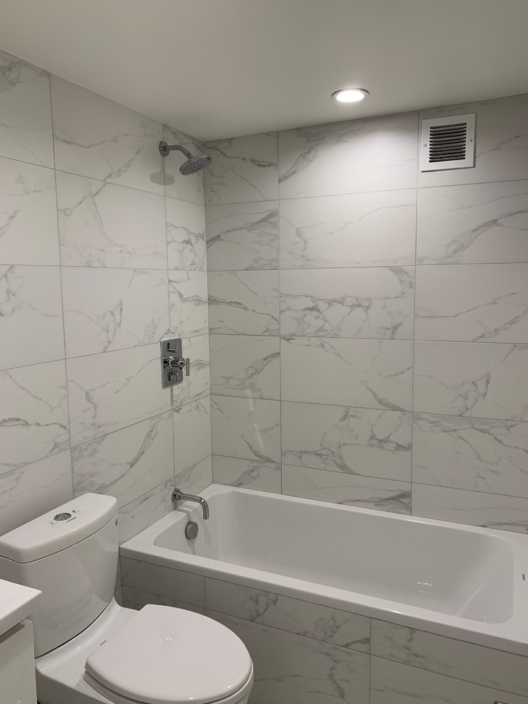 Bild på ett funkis vit vitt badrum, med släta luckor, vita skåp, ett platsbyggt badkar, en dusch/badkar-kombination, en toalettstol med separat cisternkåpa, vit kakel, marmorkakel, vita väggar, ett integrerad handfat, vitt golv och med dusch som är öppen