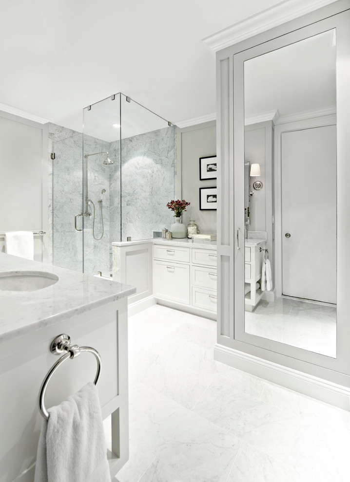 Cette photo montre une grande salle de bain principale chic avec un mur gris, un placard à porte shaker, des portes de placard blanches, un carrelage blanc, un carrelage de pierre, un plan de toilette en marbre et une douche d'angle.