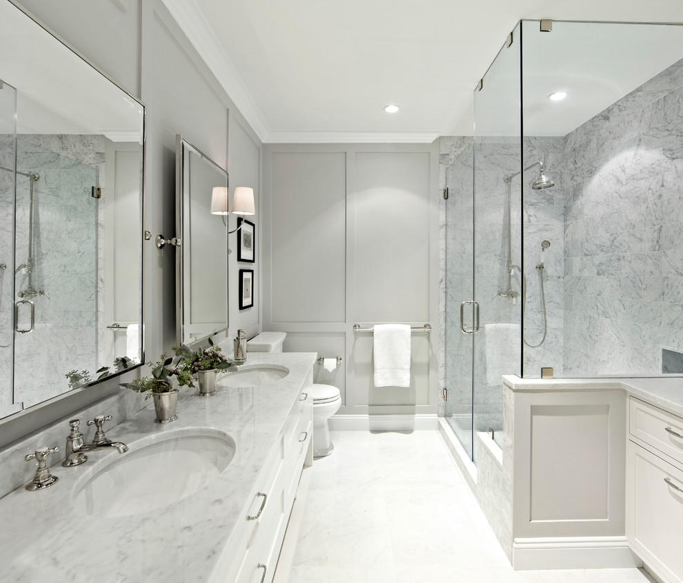 Inspiration for a large transitional master white tile and stone tile corner shower remodel in New York with shaker cabinets, white cabinets, gray walls, marble countertops and a hinged shower door