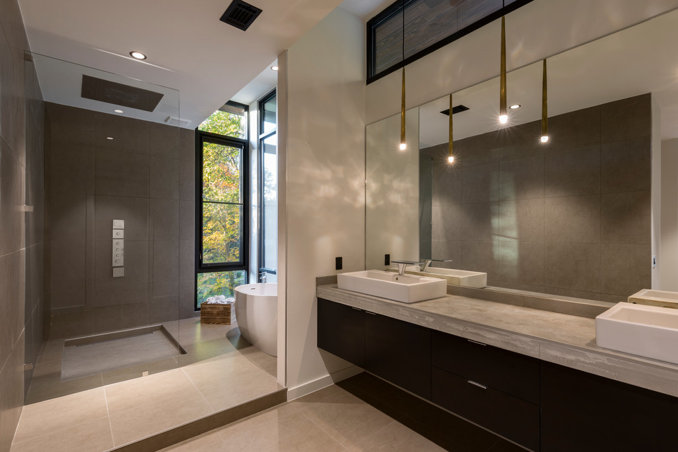Пример оригинального дизайна: главная ванная комната в стиле модернизм с темными деревянными фасадами, отдельно стоящей ванной, душем без бортиков, белой плиткой, керамогранитной плиткой, белыми стенами, полом из керамогранита, настольной раковиной, столешницей из бетона, серым полом и открытым душем