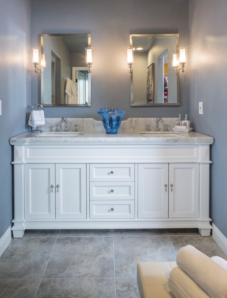 Klassisk inredning av ett mellanstort badrum, med ett undermonterad handfat, möbel-liknande, vita skåp, marmorbänkskiva, ett platsbyggt badkar, en dusch/badkar-kombination, en toalettstol med hel cisternkåpa, grå kakel, keramikplattor, blå väggar och klinkergolv i keramik