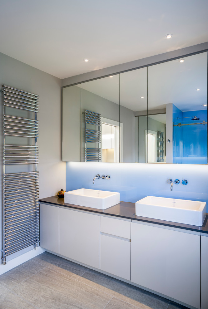 Exemple d'une salle de bain principale tendance avec un plan de toilette en surface solide, un sol en carrelage de porcelaine et un placard à porte plane.