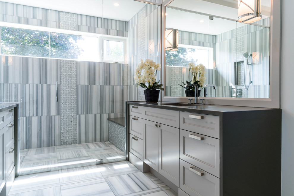 Modern inredning av ett badrum, med grå skåp, en kantlös dusch, marmorgolv, ett undermonterad handfat och bänkskiva i kvarts