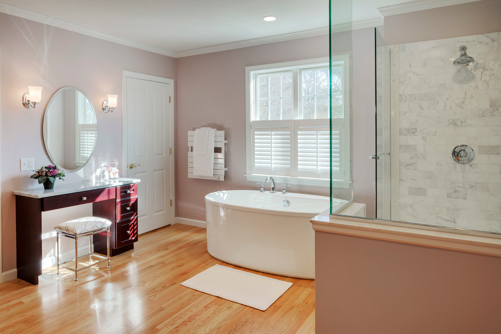 Design ideas for a large traditional ensuite bathroom in Boston with shaker cabinets, dark wood cabinets, a freestanding bath, a corner shower, a two-piece toilet, grey tiles, stone tiles, pink walls, light hardwood flooring, a submerged sink and marble worktops.