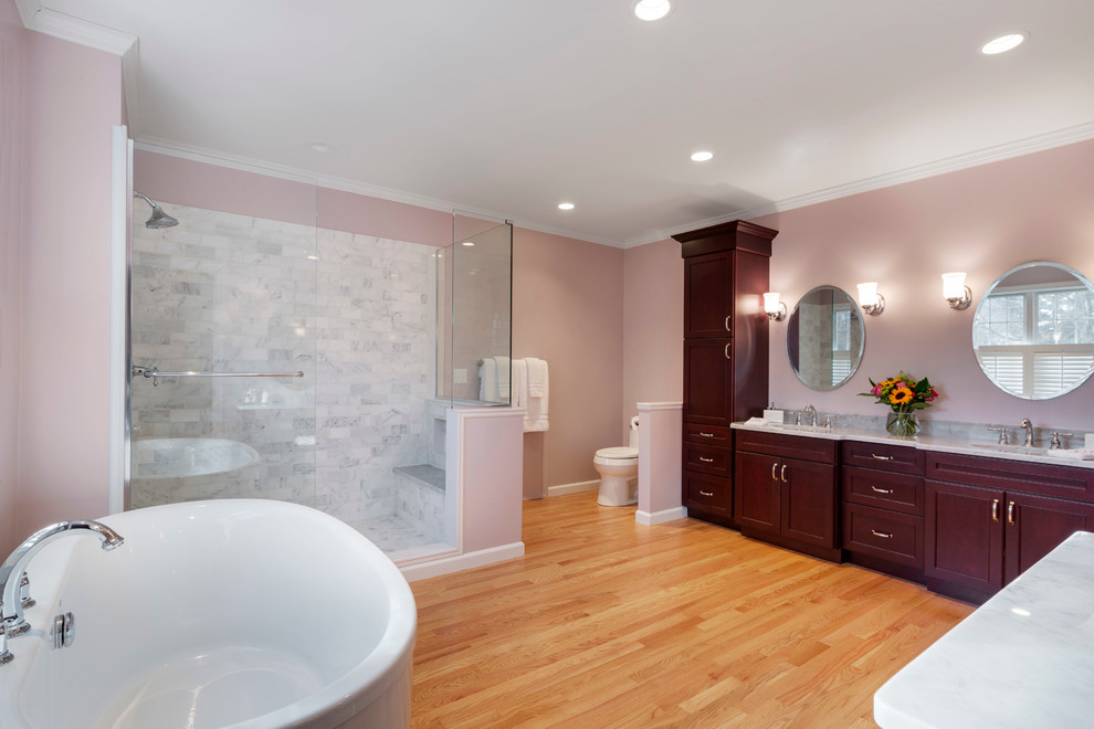 Idées déco pour une grande salle de bain principale classique en bois foncé avec un placard à porte shaker, une baignoire indépendante, une douche d'angle, WC séparés, un carrelage gris, un carrelage de pierre, un mur rose, parquet clair, un lavabo encastré et un plan de toilette en marbre.