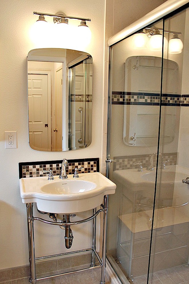 Inredning av ett klassiskt litet en-suite badrum, med ett piedestal handfat, en hörndusch, en toalettstol med separat cisternkåpa, brun kakel, glaskakel, vita väggar och klinkergolv i porslin