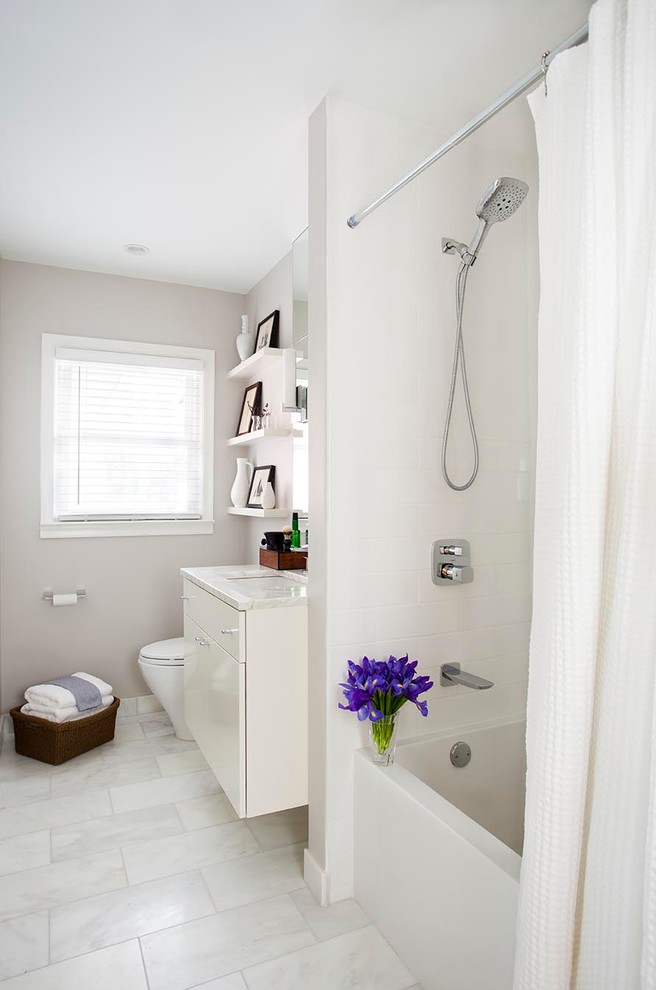 Small contemporary bathroom in Atlanta with white cabinets, an alcove bath, a shower/bath combination, white tiles, a submerged sink, marble worktops, a one-piece toilet, metro tiles, grey walls, marble flooring, flat-panel cabinets and white floors.