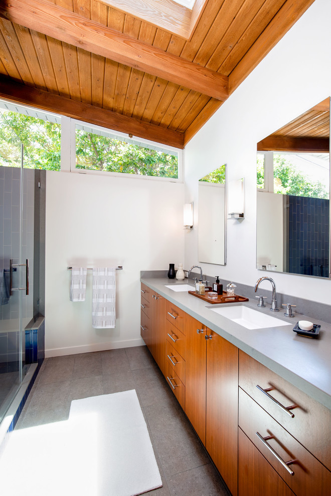 Пример оригинального дизайна: главная ванная комната среднего размера в стиле ретро с плоскими фасадами, фасадами цвета дерева среднего тона, душем в нише, унитазом-моноблоком, синей плиткой, керамической плиткой, белыми стенами, полом из керамической плитки, врезной раковиной, столешницей из искусственного кварца, серым полом, душем с распашными дверями и серой столешницей