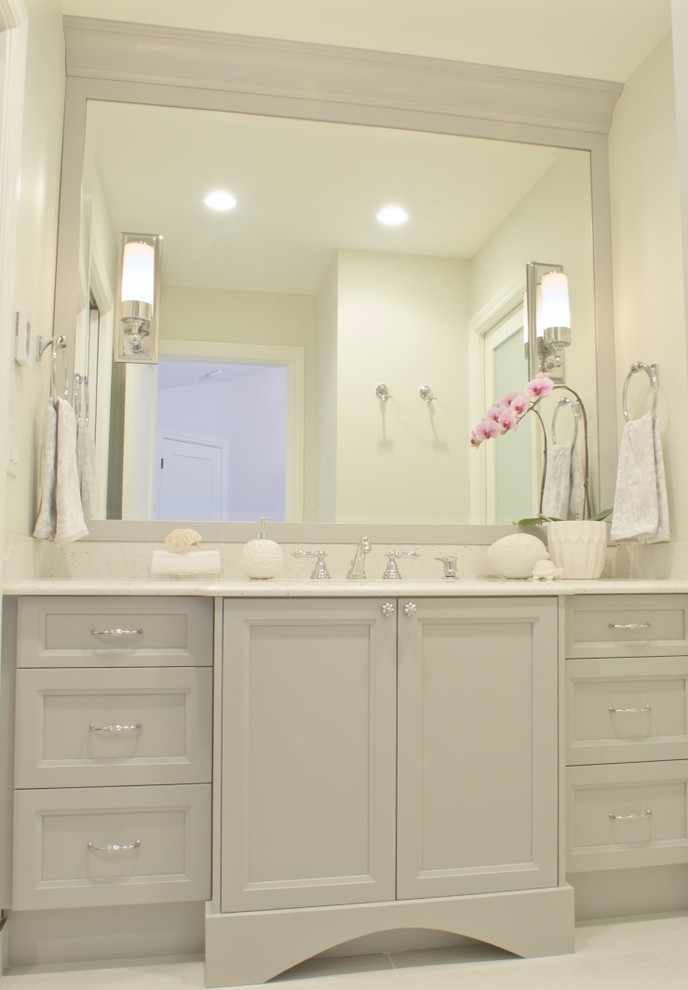 Klassisk inredning av ett litet badrum, med luckor med infälld panel, grå skåp, ett platsbyggt badkar, en dusch/badkar-kombination, en toalettstol med hel cisternkåpa, grå kakel, keramikplattor, beige väggar, klinkergolv i keramik, ett undermonterad handfat och granitbänkskiva