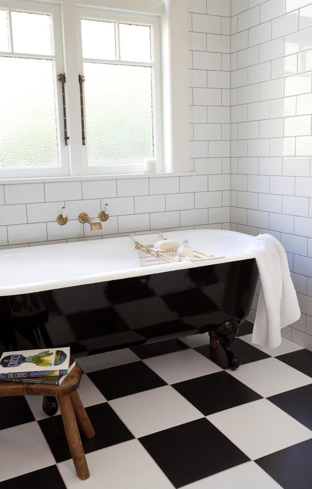 Bild på ett stort vintage en-suite badrum, med ett badkar med tassar, en toalettstol med separat cisternkåpa, vit kakel, porslinskakel, vita väggar, klinkergolv i porslin, ett avlångt handfat, bänkskiva i akrylsten och en öppen dusch