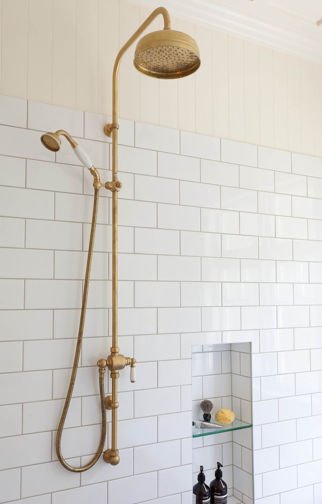 Bild på ett stort vintage en-suite badrum, med ett badkar med tassar, en öppen dusch, en toalettstol med separat cisternkåpa, vit kakel, porslinskakel, vita väggar, klinkergolv i porslin, ett avlångt handfat och bänkskiva i akrylsten