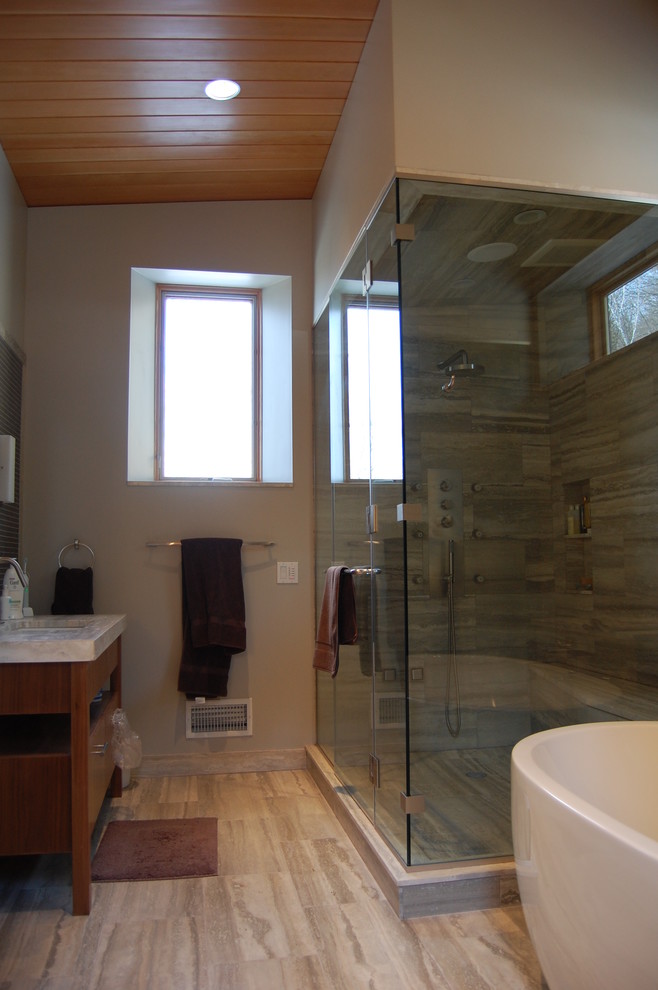 Design ideas for a large modern ensuite bathroom in Boston with medium wood cabinets, a freestanding bath, a corner shower, grey walls, flat-panel cabinets, a two-piece toilet, light hardwood flooring, a submerged sink, marble worktops, brown floors and a hinged door.