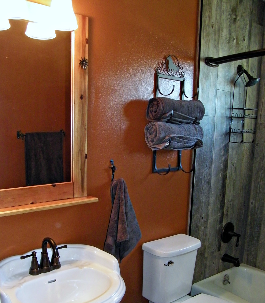 Immagine di una piccola stanza da bagno con doccia rustica con vasca da incasso, vasca/doccia, WC monopezzo, piastrelle grigie, piastrelle in gres porcellanato, pareti arancioni e pavimento in gres porcellanato