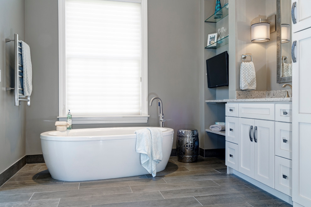 Example of a transitional master gray tile and wood-look tile ceramic tile freestanding bathtub design in Columbus with an undermount sink, white cabinets, quartz countertops, a one-piece toilet and gray walls