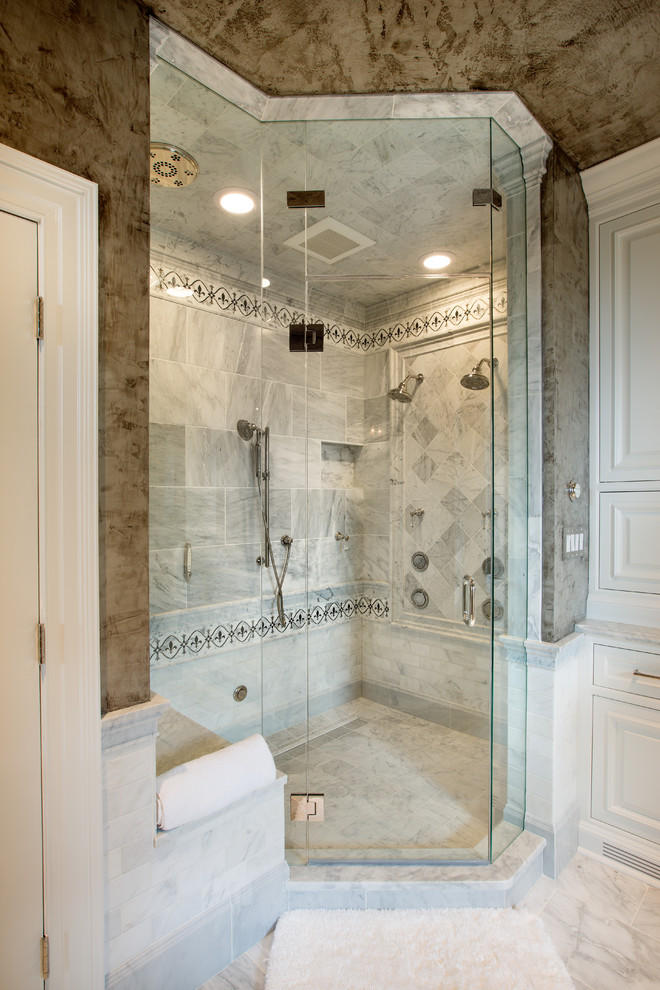Cette photo montre une grande salle de bain principale chic avec un lavabo encastré, un placard à porte affleurante, des portes de placard blanches, un plan de toilette en marbre, une baignoire en alcôve, une douche double, un carrelage gris, un carrelage de pierre, un mur gris et un sol en marbre.