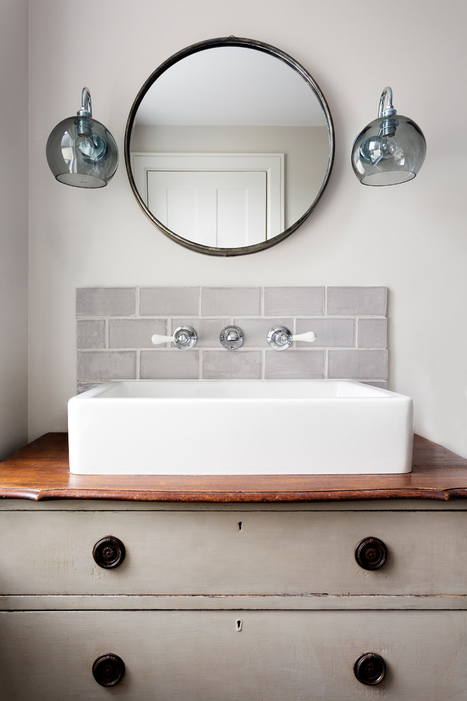 Photo of a contemporary bathroom in London with flat-panel cabinets, distressed cabinets, grey tiles, grey walls, a vessel sink and wooden worktops.