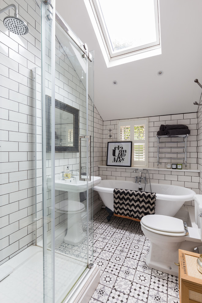 This is an example of a classic bathroom in London with a claw-foot bath, a corner shower, a two-piece toilet, white tiles, metro tiles, a pedestal sink and a sliding door.