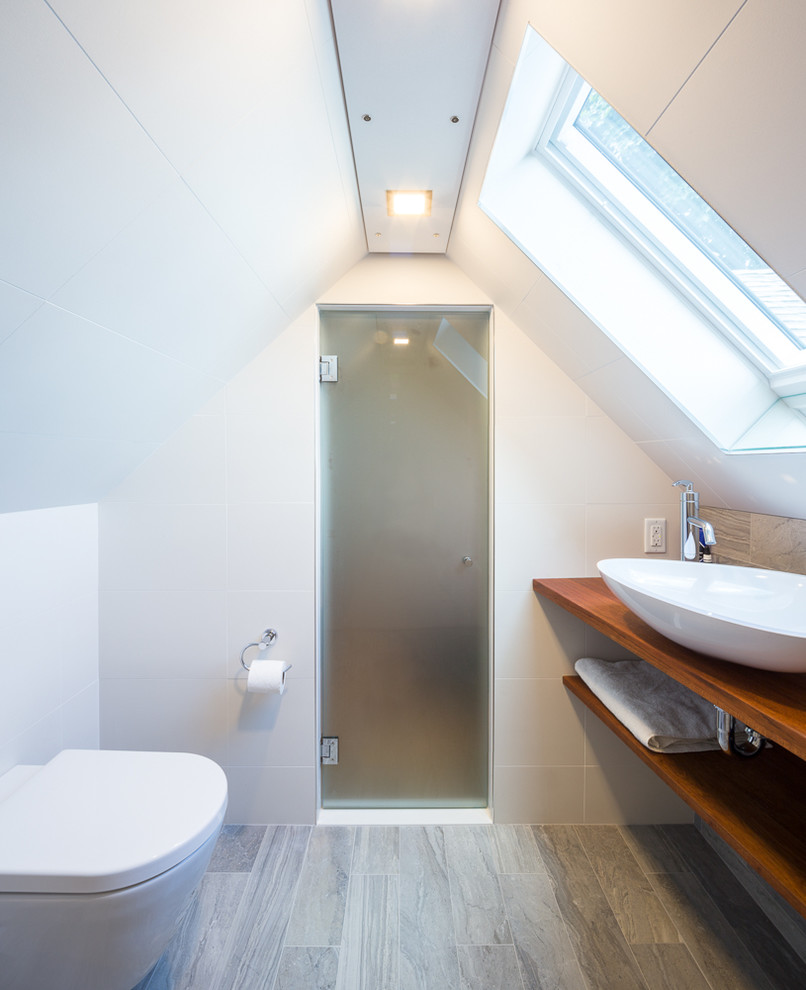Modern inredning av ett litet en-suite badrum, med våtrum, en vägghängd toalettstol, flerfärgad kakel, klinkergolv i keramik, ett fristående handfat och träbänkskiva