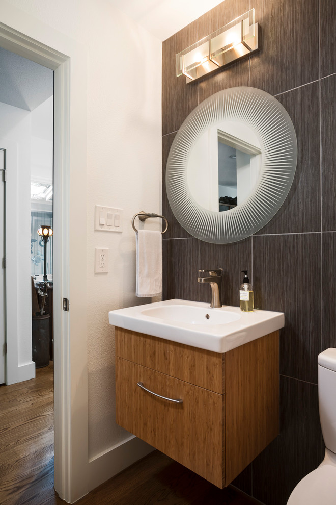 Kleines Modernes Badezimmer mit flächenbündigen Schrankfronten, hellbraunen Holzschränken, grauen Fliesen, Porzellanfliesen, weißer Wandfarbe, braunem Holzboden und Einbauwaschbecken in Austin