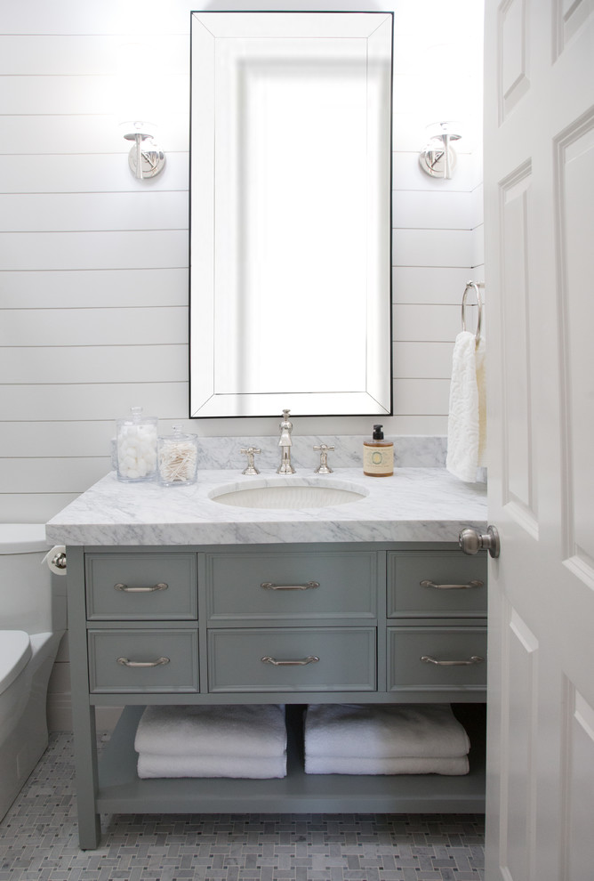Cette photo montre une petite salle d'eau chic avec WC à poser, du carrelage en marbre, un mur blanc, un sol en carrelage de terre cuite, un lavabo encastré, un plan de toilette en marbre, un placard en trompe-l'oeil, des portes de placard grises, un carrelage gris et un sol gris.