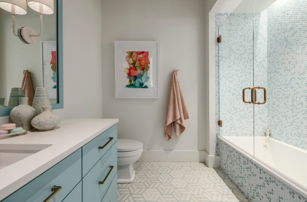 Modelo de cuarto de baño tradicional renovado con armarios con paneles lisos, puertas de armario azules, bañera encastrada, baldosas y/o azulejos multicolor, baldosas y/o azulejos en mosaico, paredes blancas, lavabo bajoencimera, suelo multicolor y encimeras blancas