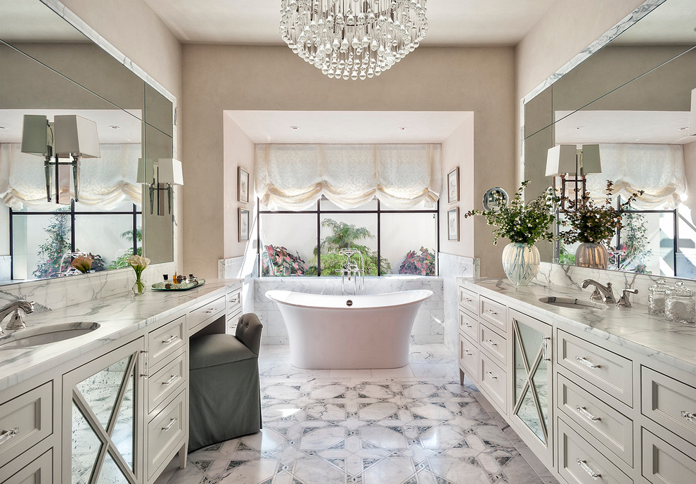Inspiration for a mediterranean bathroom in Austin with recessed-panel cabinets, grey cabinets, a freestanding bath, beige walls and a submerged sink.