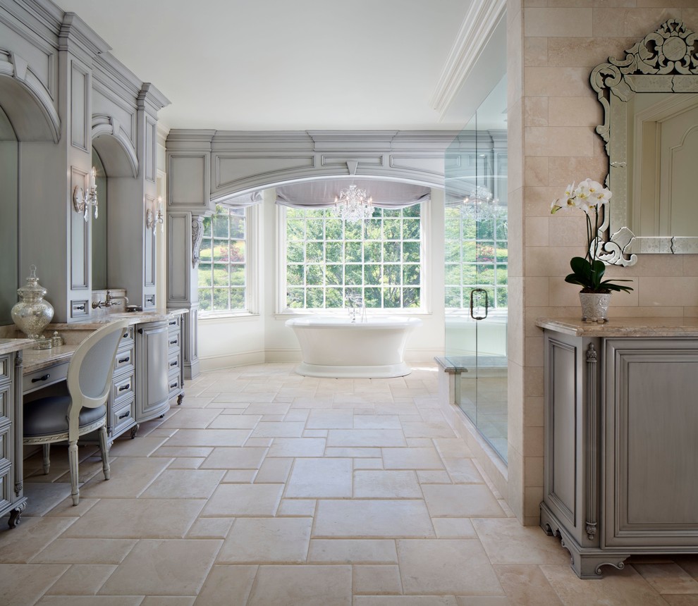 На фото: ванная комната в классическом стиле с врезной раковиной, фасадами островного типа, серыми фасадами, мраморной столешницей, отдельно стоящей ванной, унитазом-моноблоком, серой плиткой и каменной плиткой с