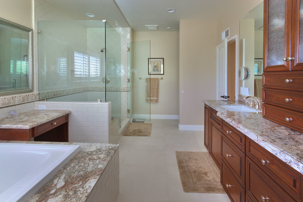Photo of a large traditional ensuite bathroom in Los Angeles with recessed-panel cabinets, dark wood cabinets, a built-in bath, a corner shower, a one-piece toilet, white tiles, metro tiles, beige walls, a submerged sink and granite worktops.